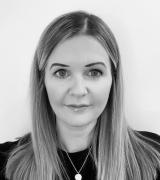 Laura Thorne HR Manager smiling with necklace to front and black clothing in black and white filtered image